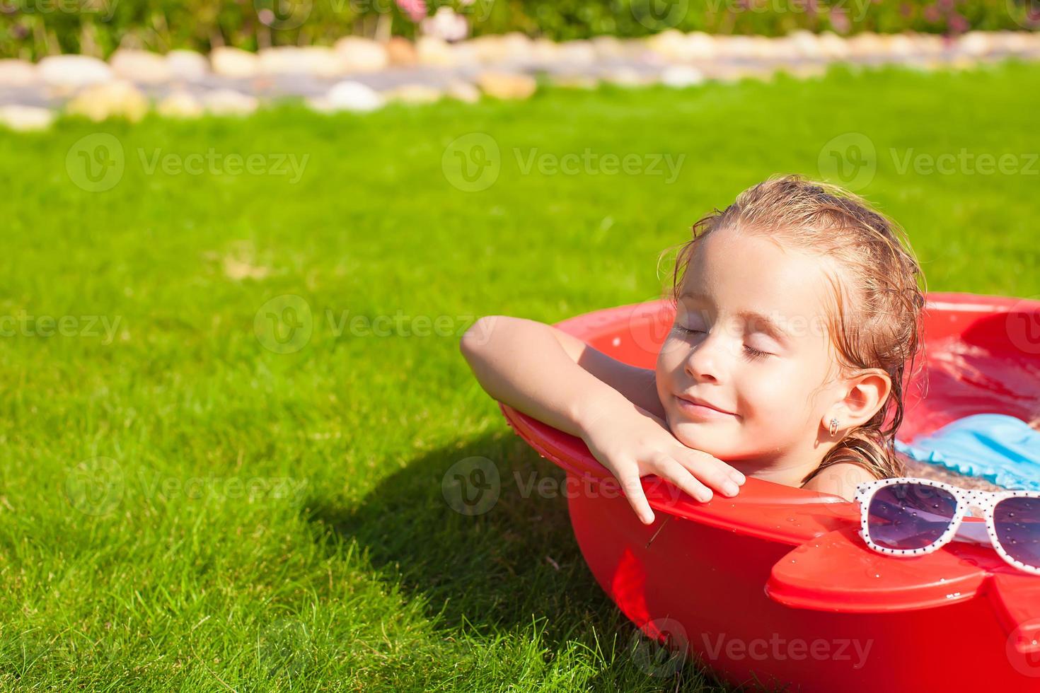 Portrait of relaxing adorable little girl enjoying her vacation in small pool outdoor photo