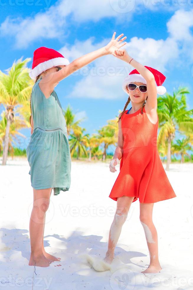 Adorable little kids in Santa hat during Christmas beach vacation. New Year on the beach photo