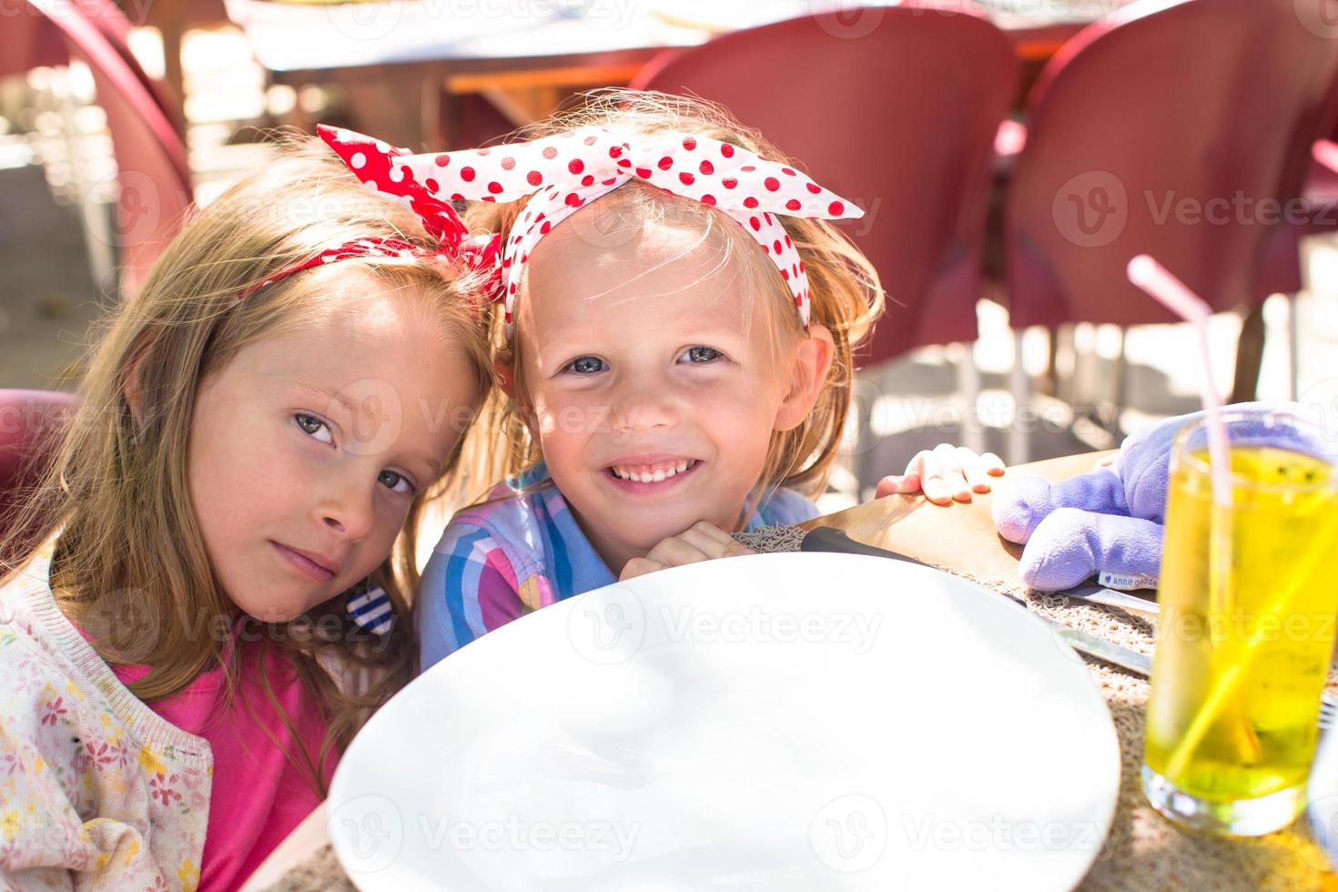Adorable little girls in outdoor cafe photo