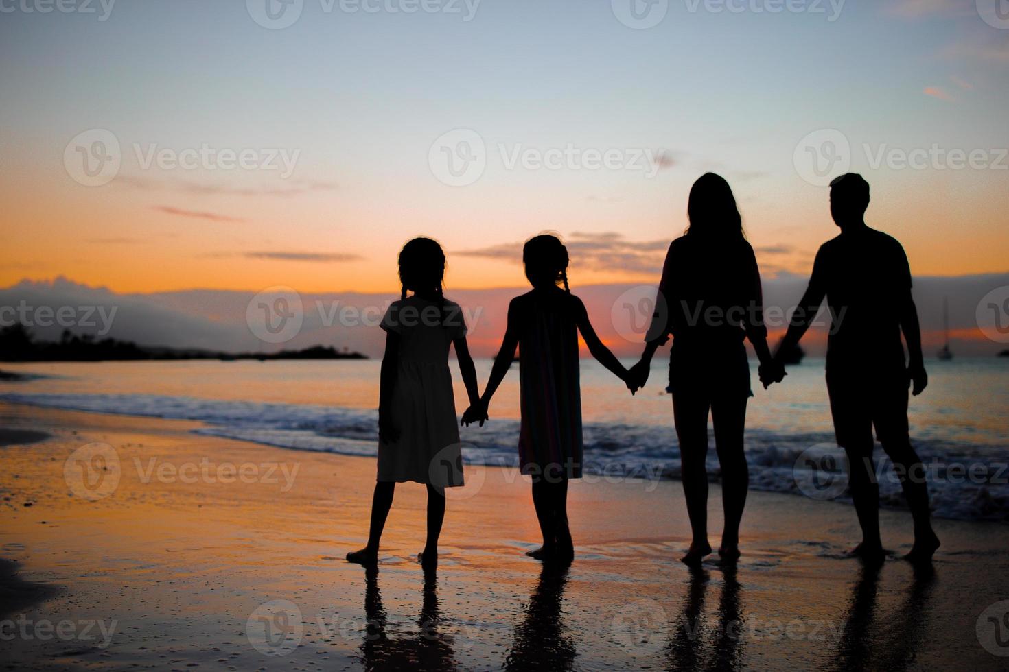 Family silhouette in the sunset at the beach photo