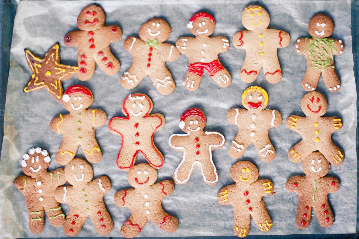 Raw gingerbread men with glaze on a baking sheet photo