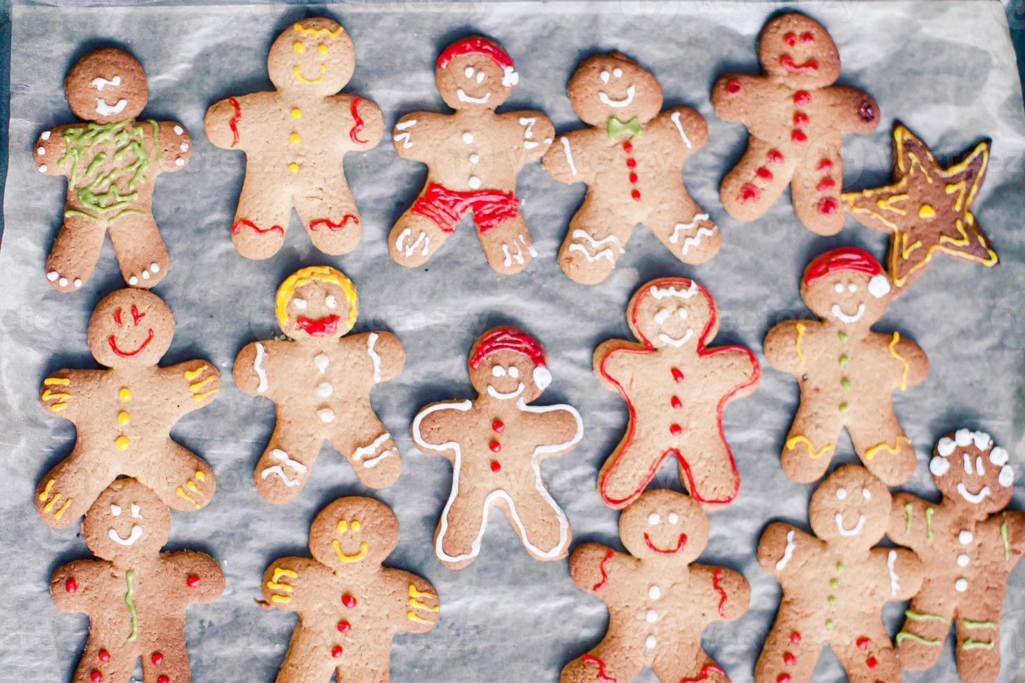 Raw gingerbread men with glaze on a baking sheet photo