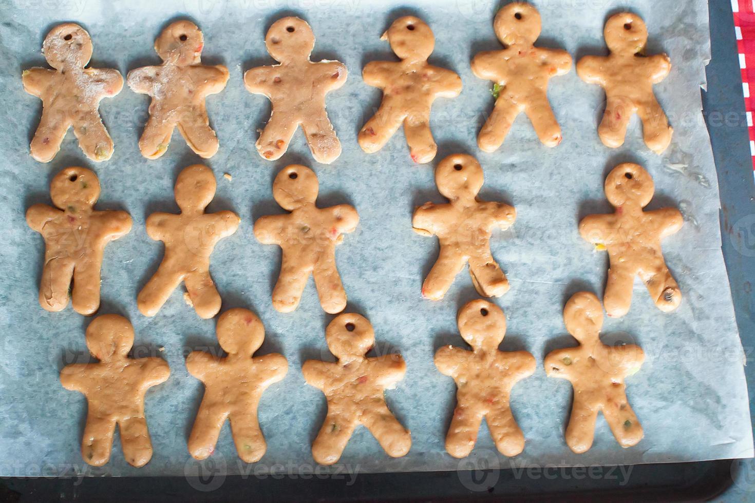 Raw gingerbread men on a baking photo