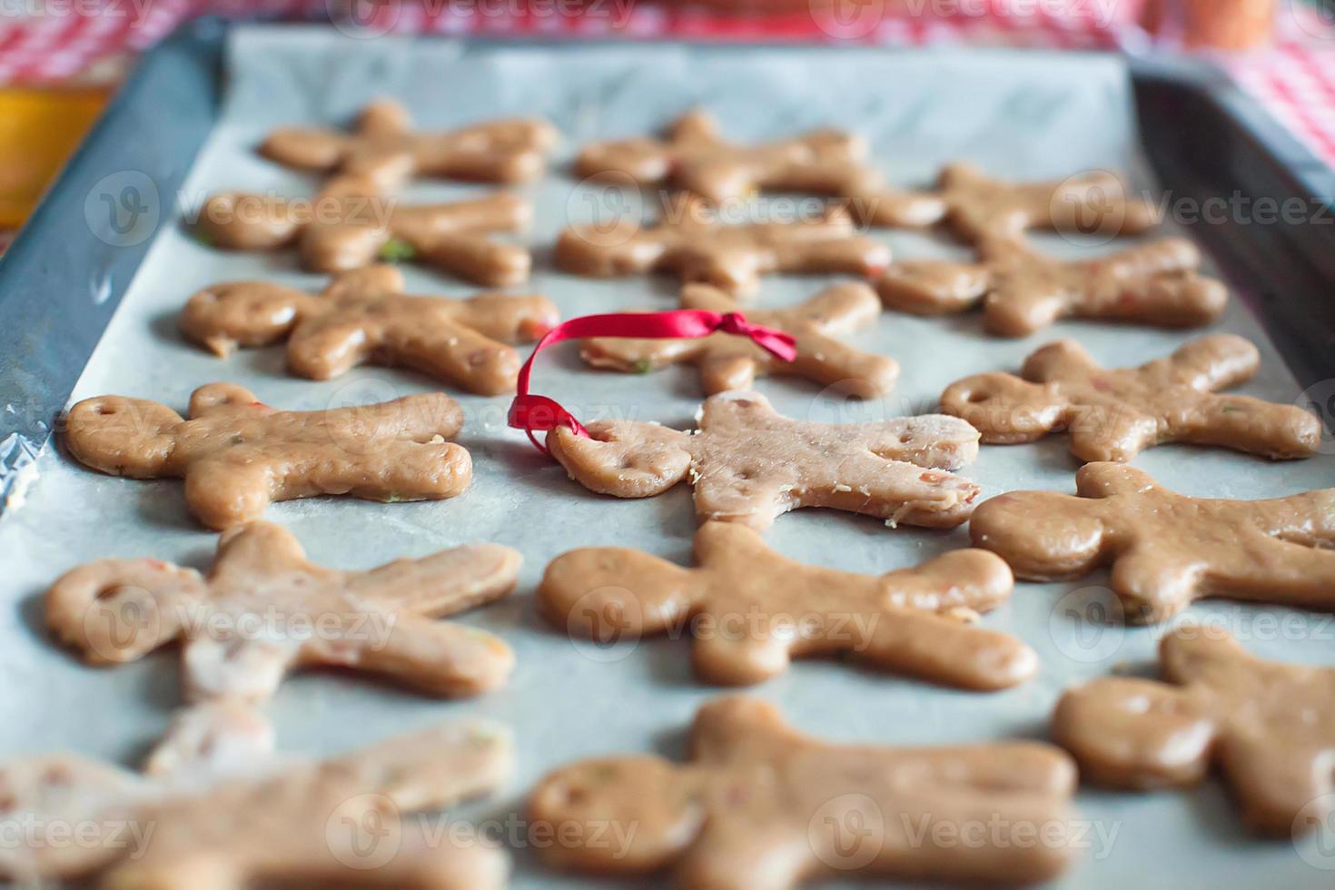 Raw gingerbread men on a baking photo