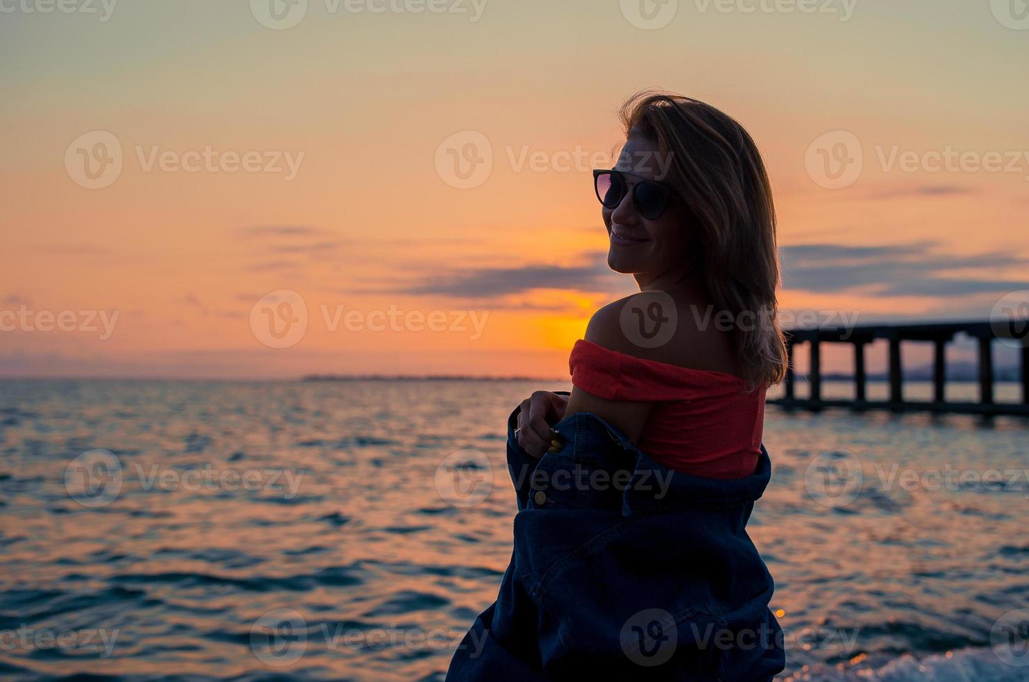 Outdoor fashion portrait of stylish girl wearing trendy sunglasses and jeans jacket on the beach. photo