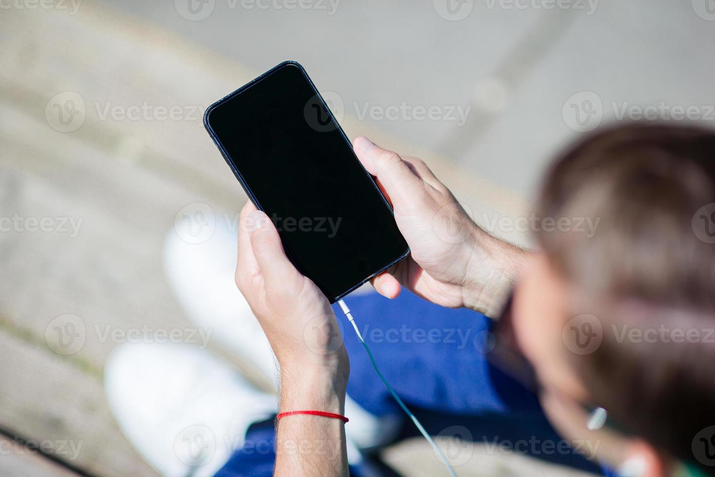 Closeup of cellphone display in male hands outdoors on the street. Man using mobile smartphone. photo