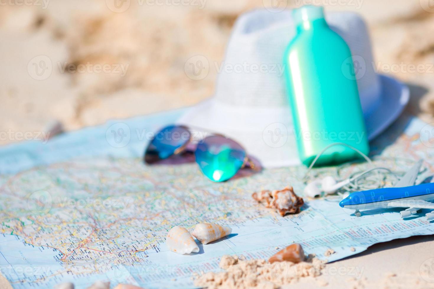 Traveling concept. Hat, suncream, sunglasses on a map of the world. photo