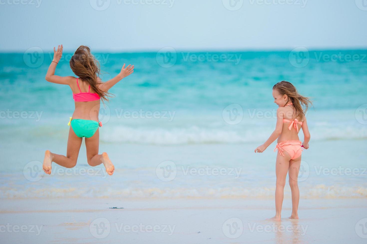 Little girls playing together at shallow water on vacation photo