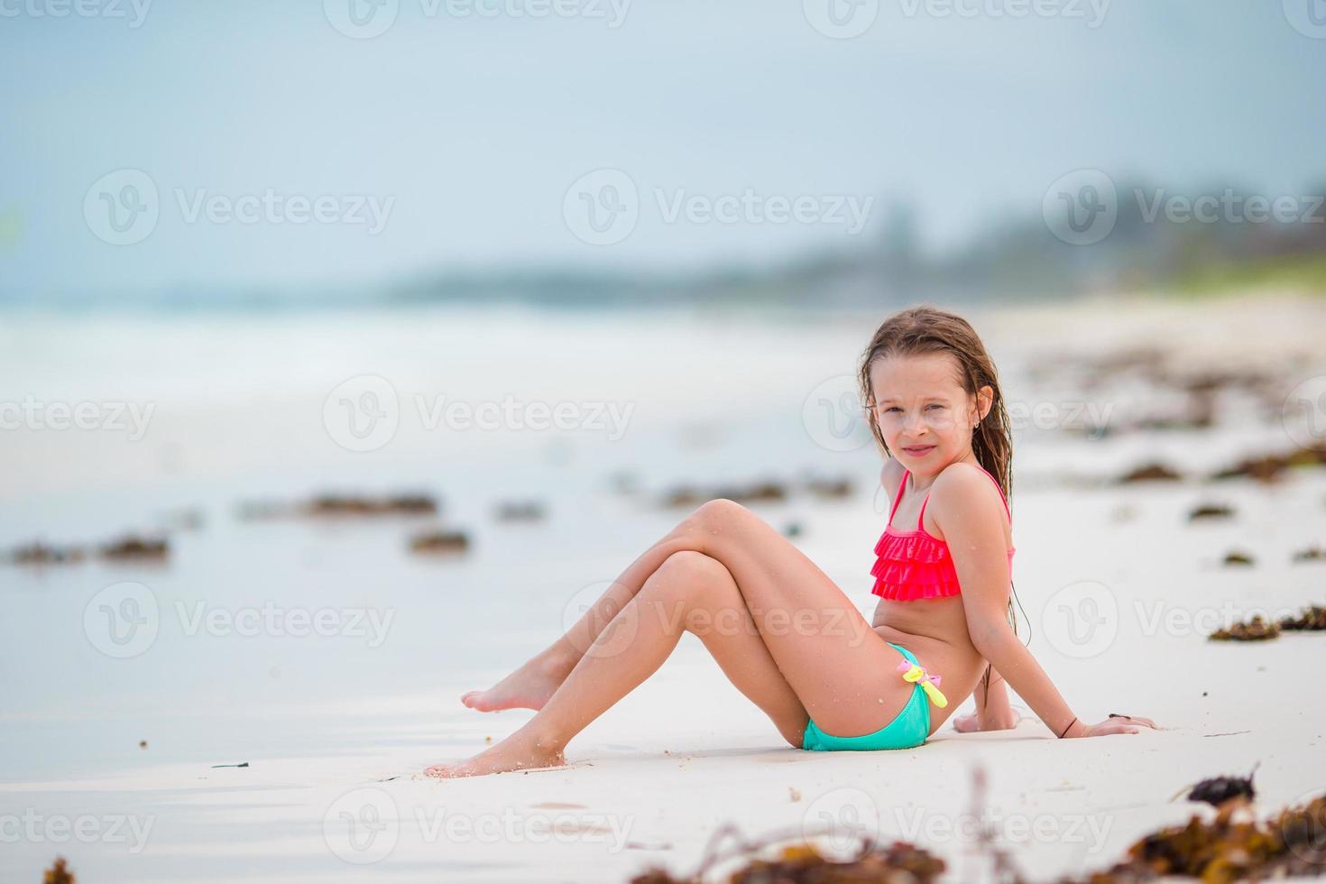 Adorable little girl have fun at shallow water on white beach photo