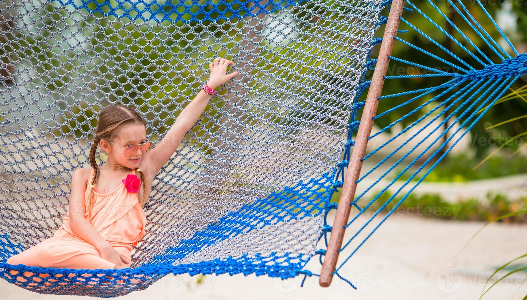 Adorable little girl swinging in hammock at beach photo