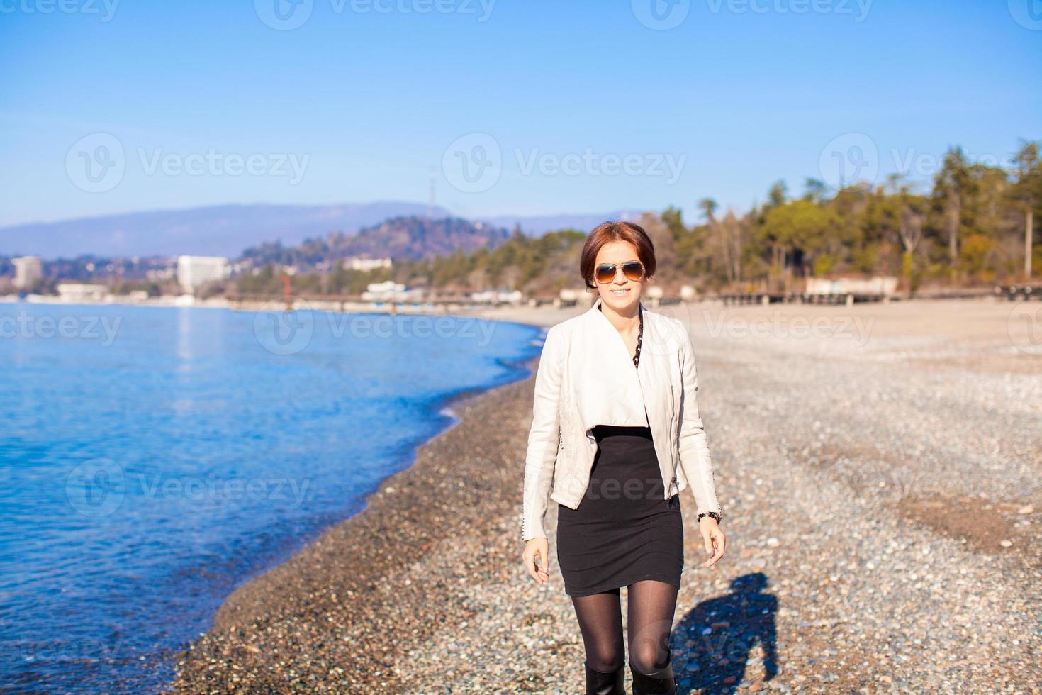 Beautiful young woman walking on the beach in winter sunny day alone photo