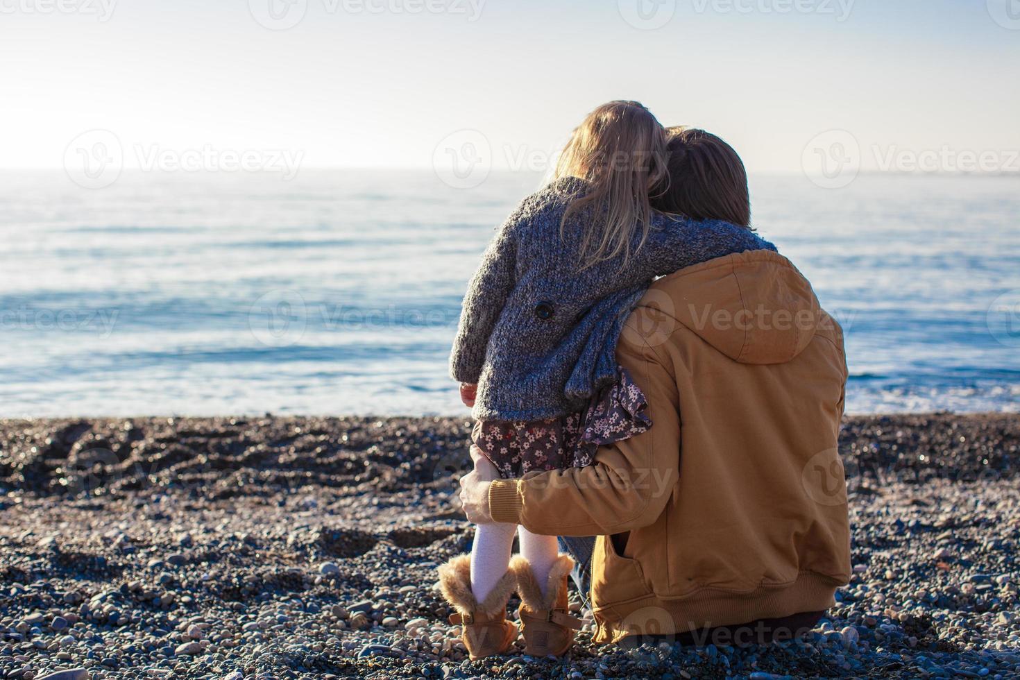 Back view of Young father and little girl at the beach on a sunny winter day photo