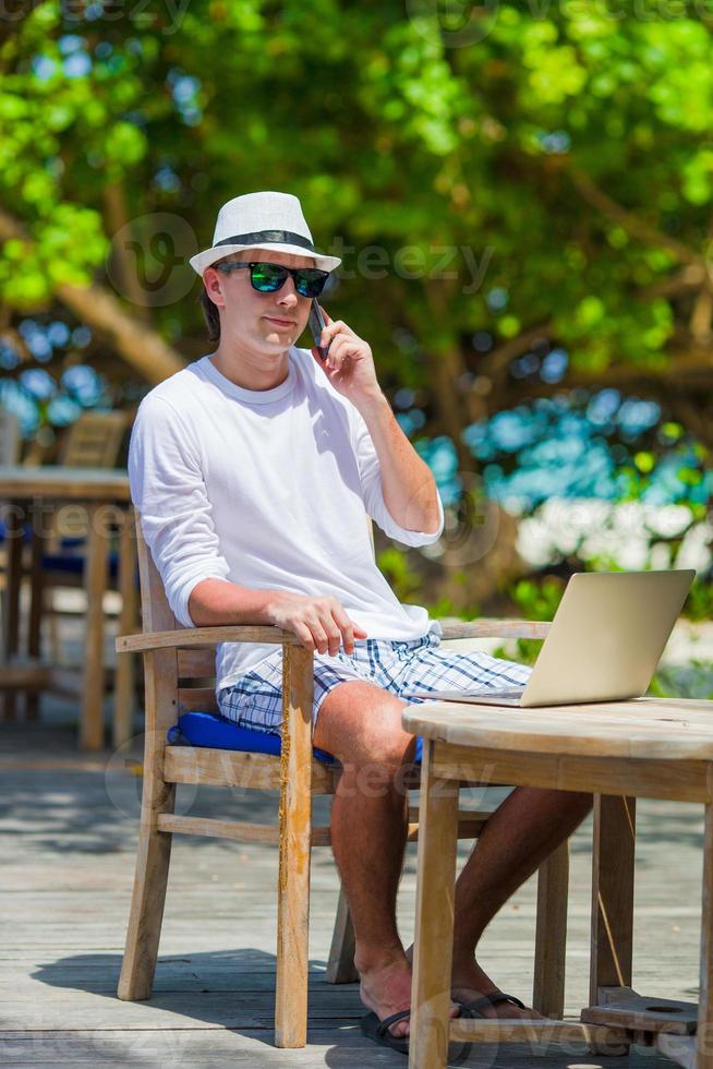 joven hombre de negocios llamando por teléfono celular en playa blanca foto