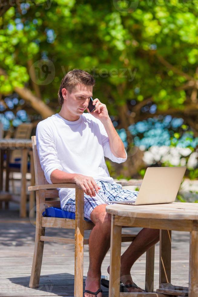 joven hombre de negocios llamando por teléfono celular en un café al aire libre foto