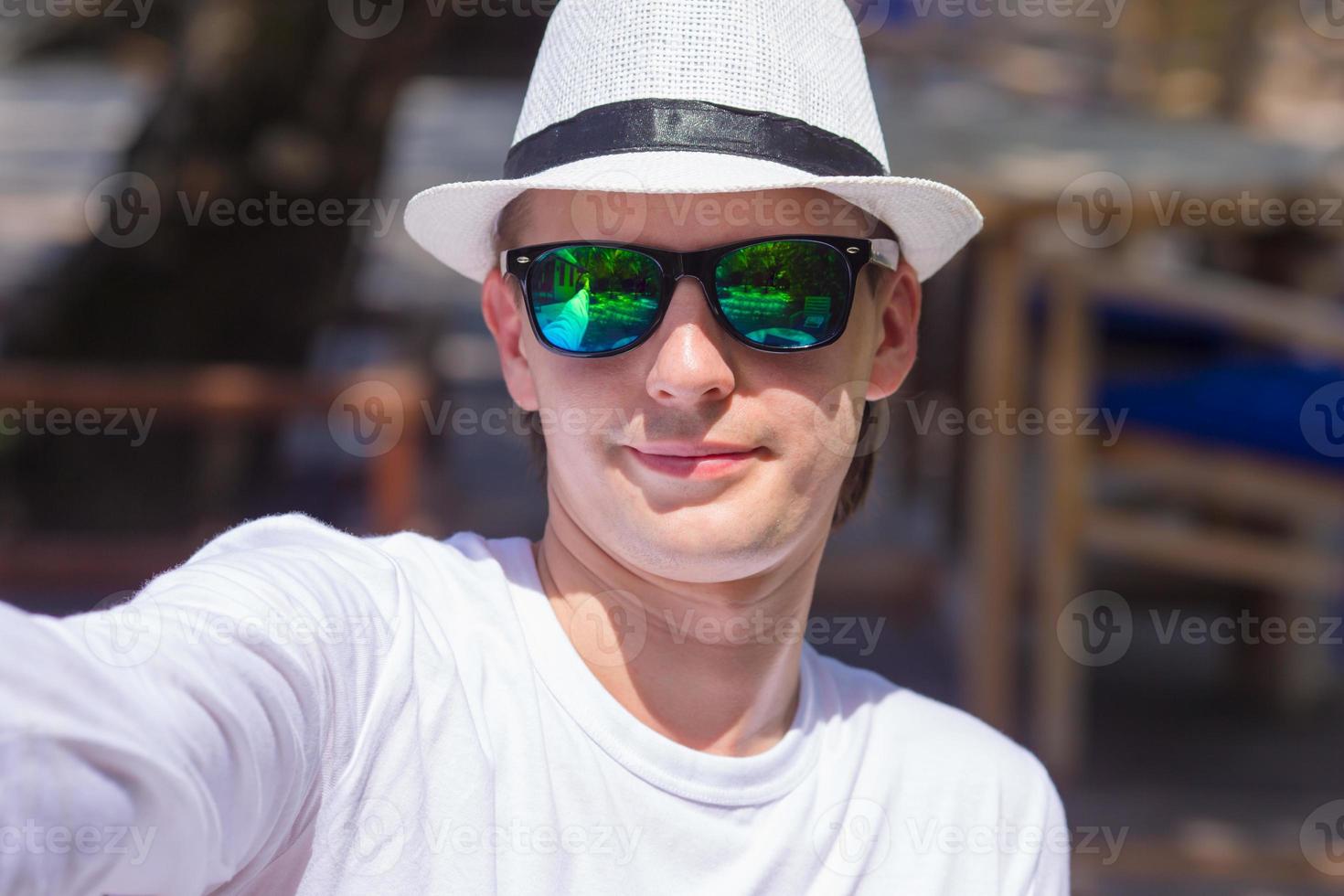 Young man making his selfie on beach at outdorr cafe photo
