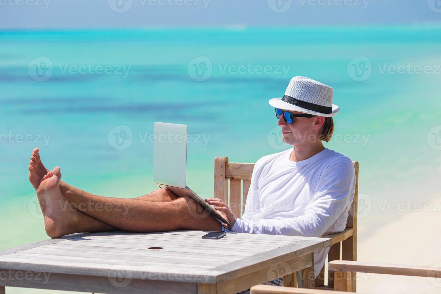 Young man with tablet computer on tropical beach photo