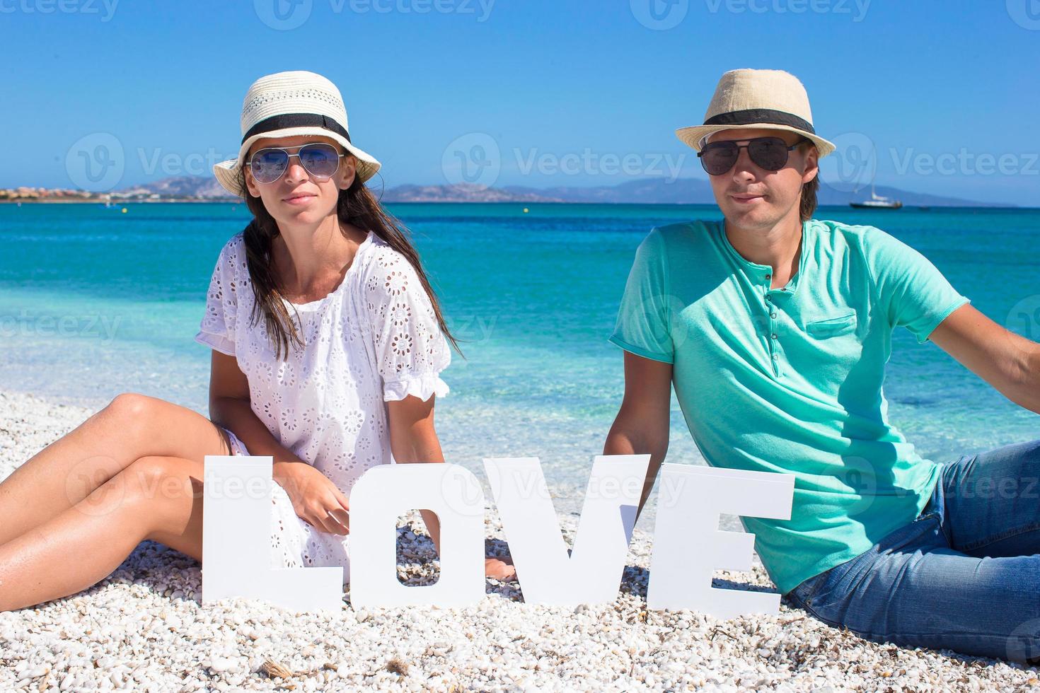 Young beautiful family sitting on the beach with word Love photo