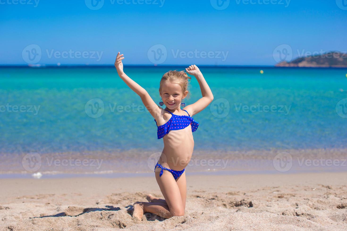 Adorable little girl have fun on tropical white sandy beach photo