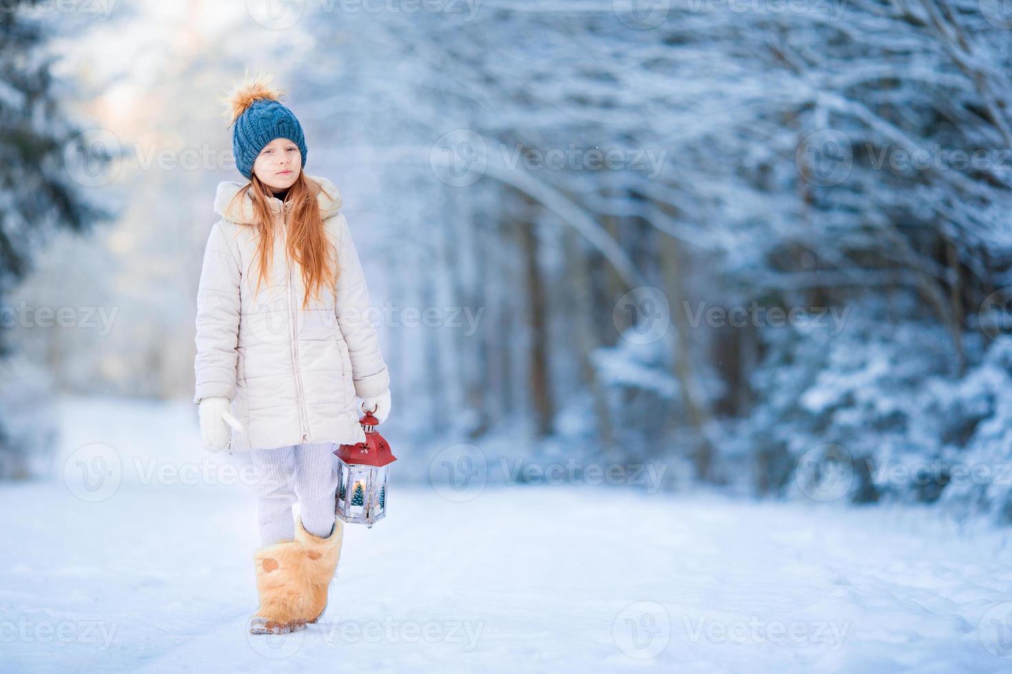 Little girl with latern in frozen forest on Christmas eve photo