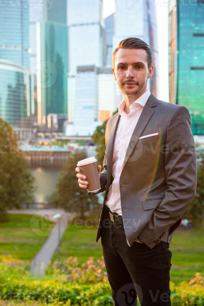 Businessman looking on copy space while standing against glass skyscraper photo