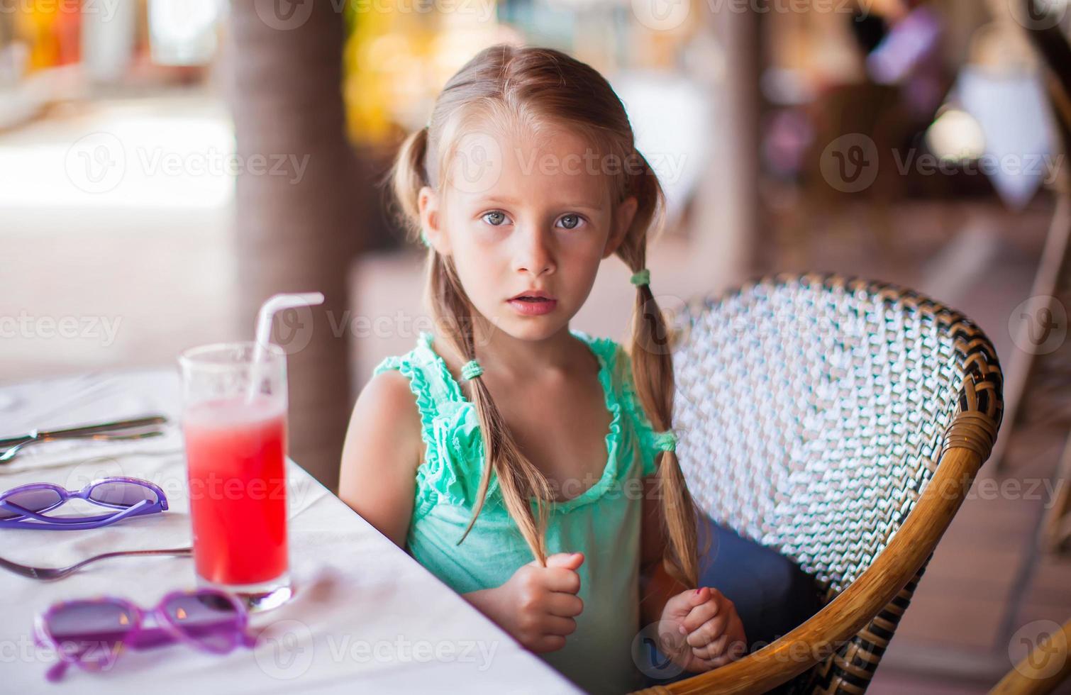Adorable little girl having breakfast and drinking fruit cocktail photo