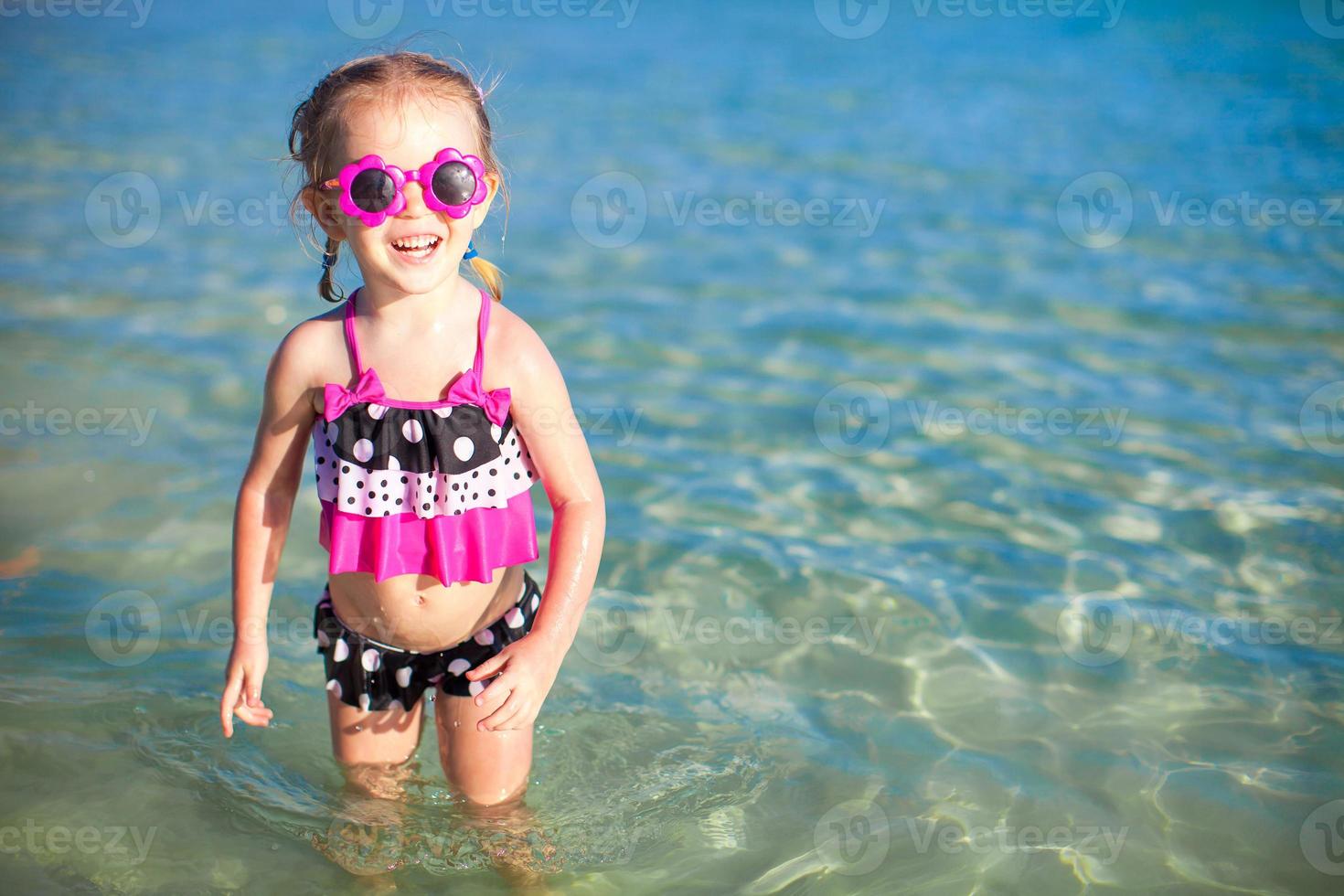 Happy little girl having fun at shallow water photo