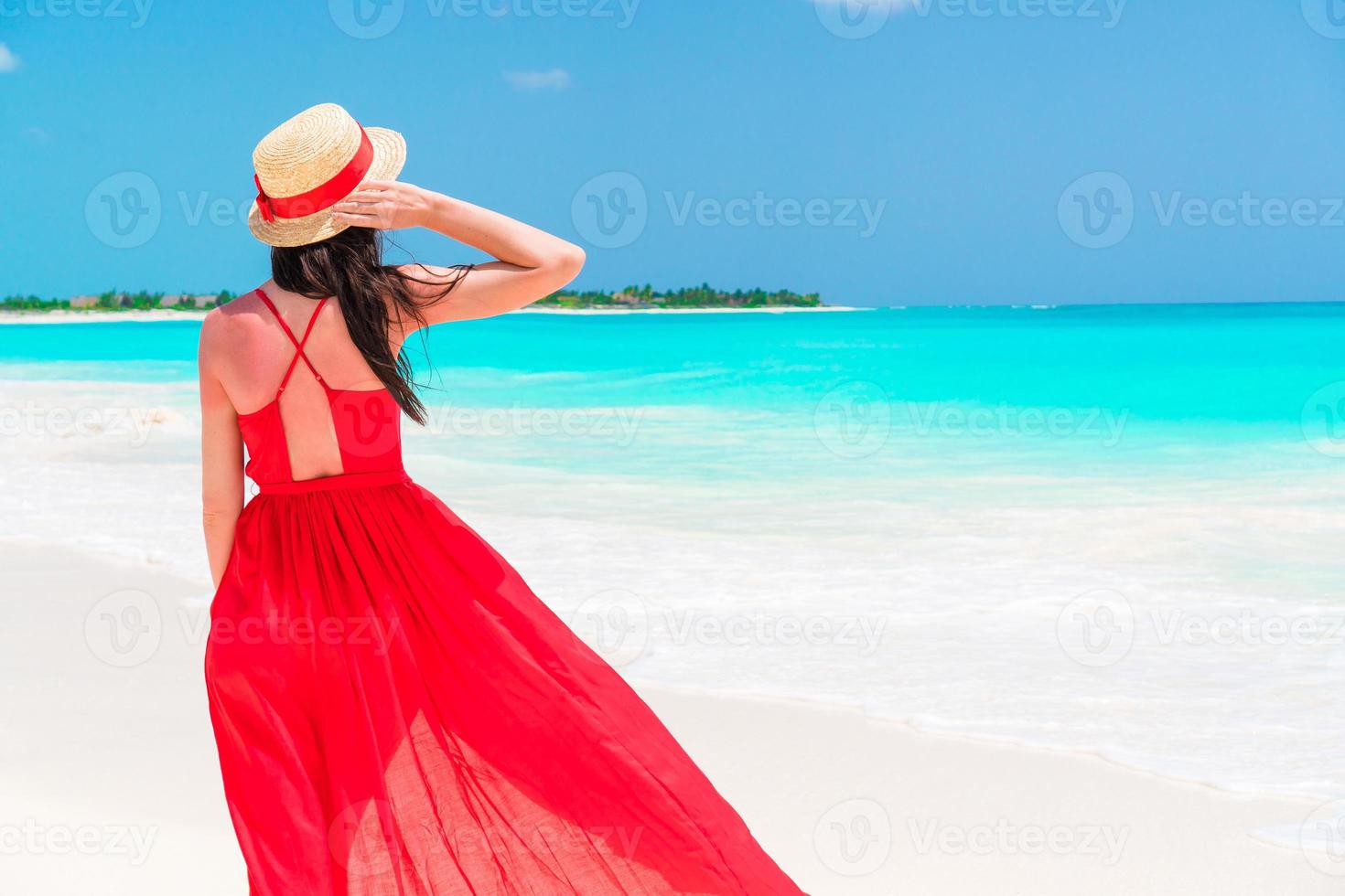 hermosa mujer en la costa tropical. niña en hermoso vestido rojo fondo el mar foto