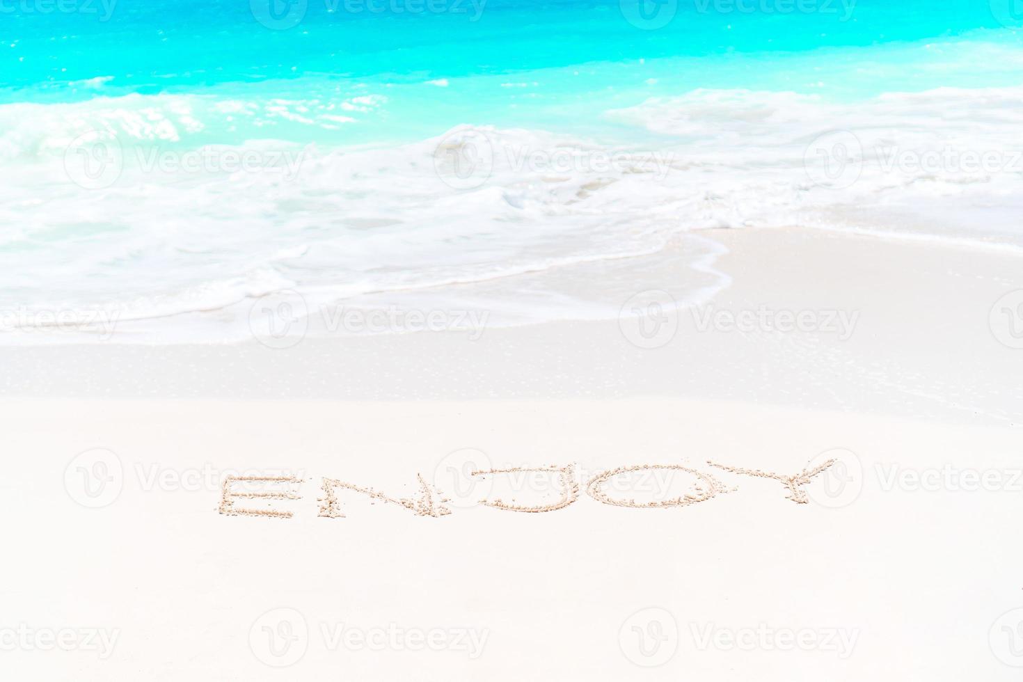 Handwritten on sandy beach with soft ocean wave on background photo