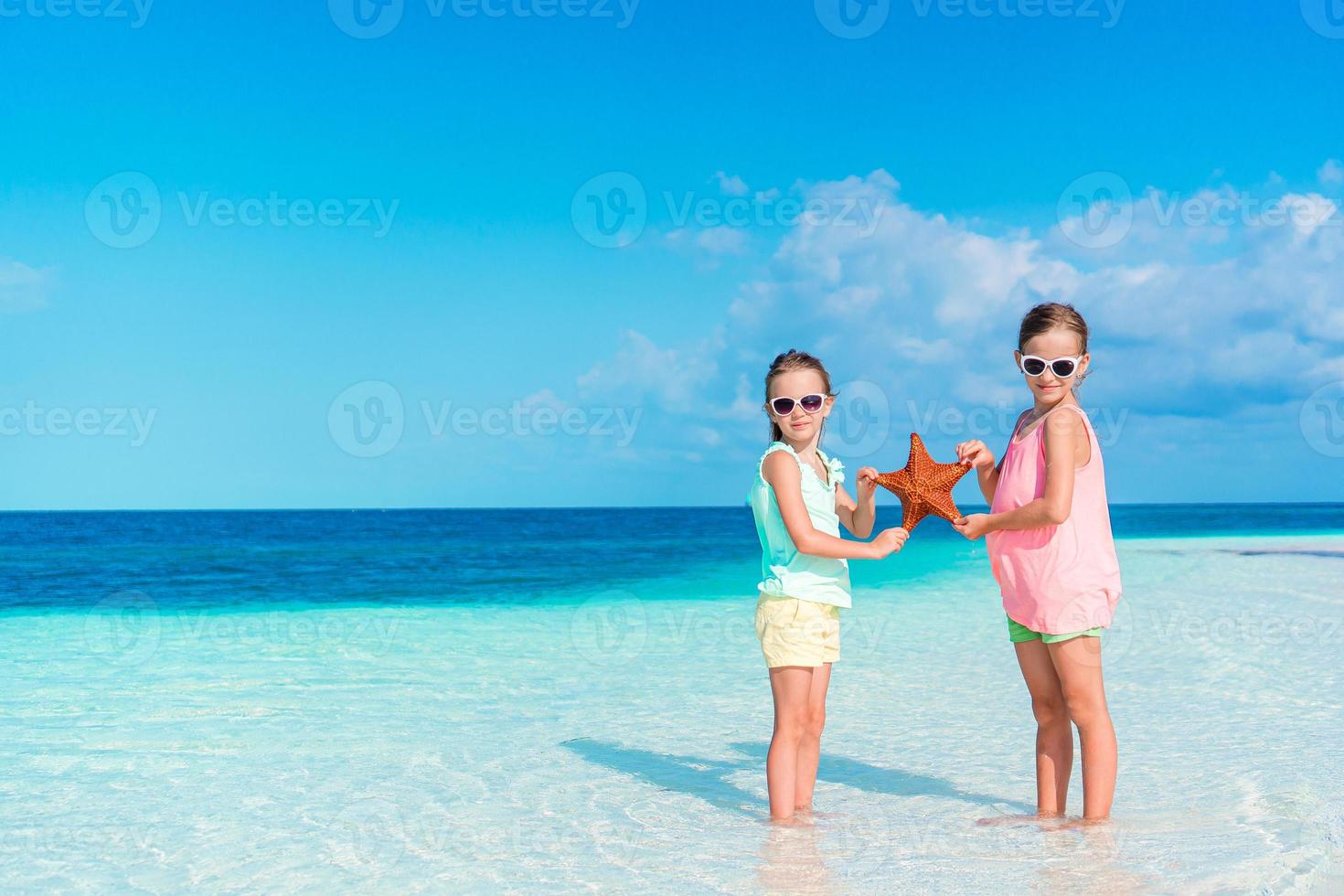 Two little happy girls have a lot of fun at tropical beach playing together photo