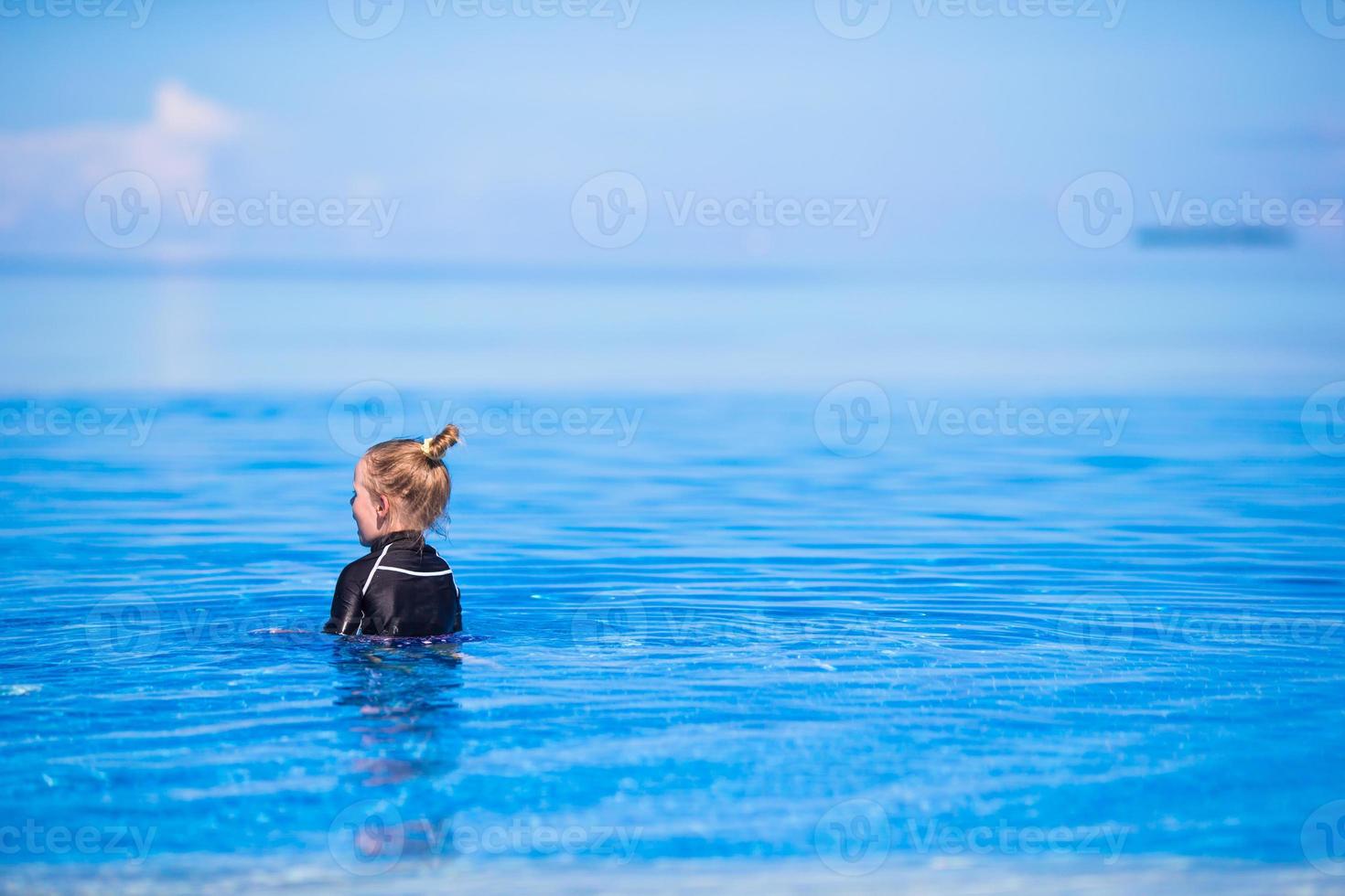 feliz hermosa niña divirtiéndose en la piscina al aire libre foto