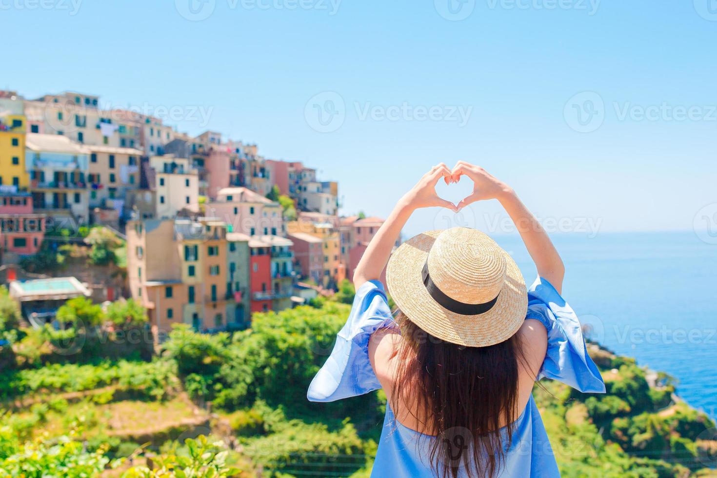 Happy girl making with hands heart shape on the old coastal village in Cinque Terre National Park. European vacation. photo