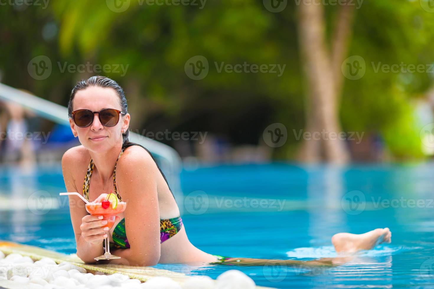 Beautiful young girl relaxing in the swimming pool photo