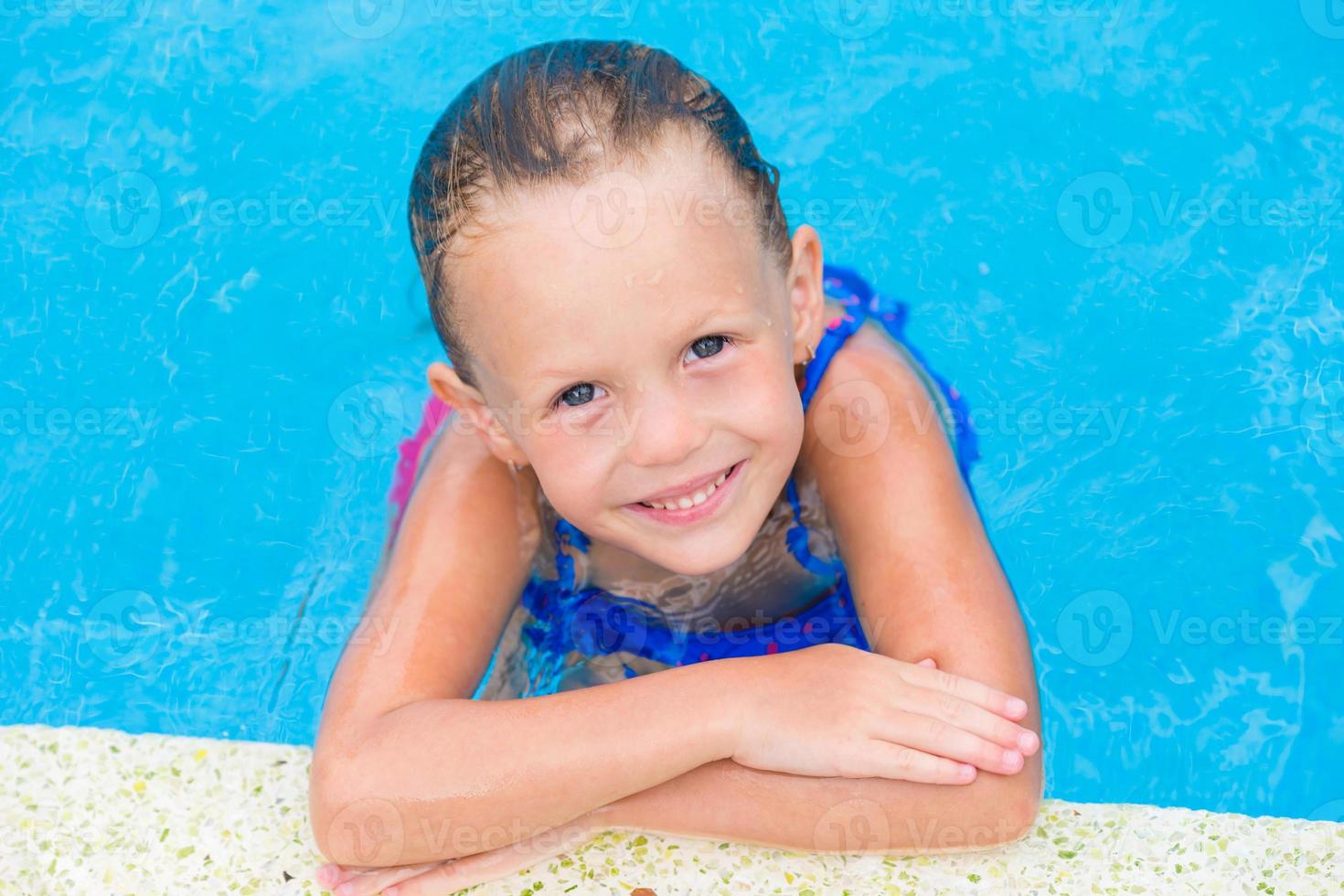 Portrait of smiling happy cute girl in outdoor swimming pool photo