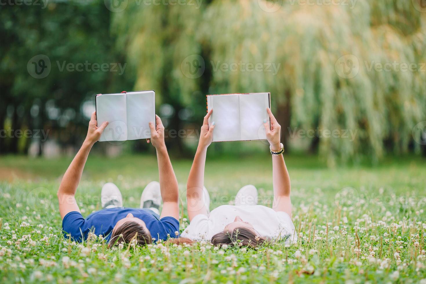 joven pareja romántica tumbada en el parque y leyendo libros foto