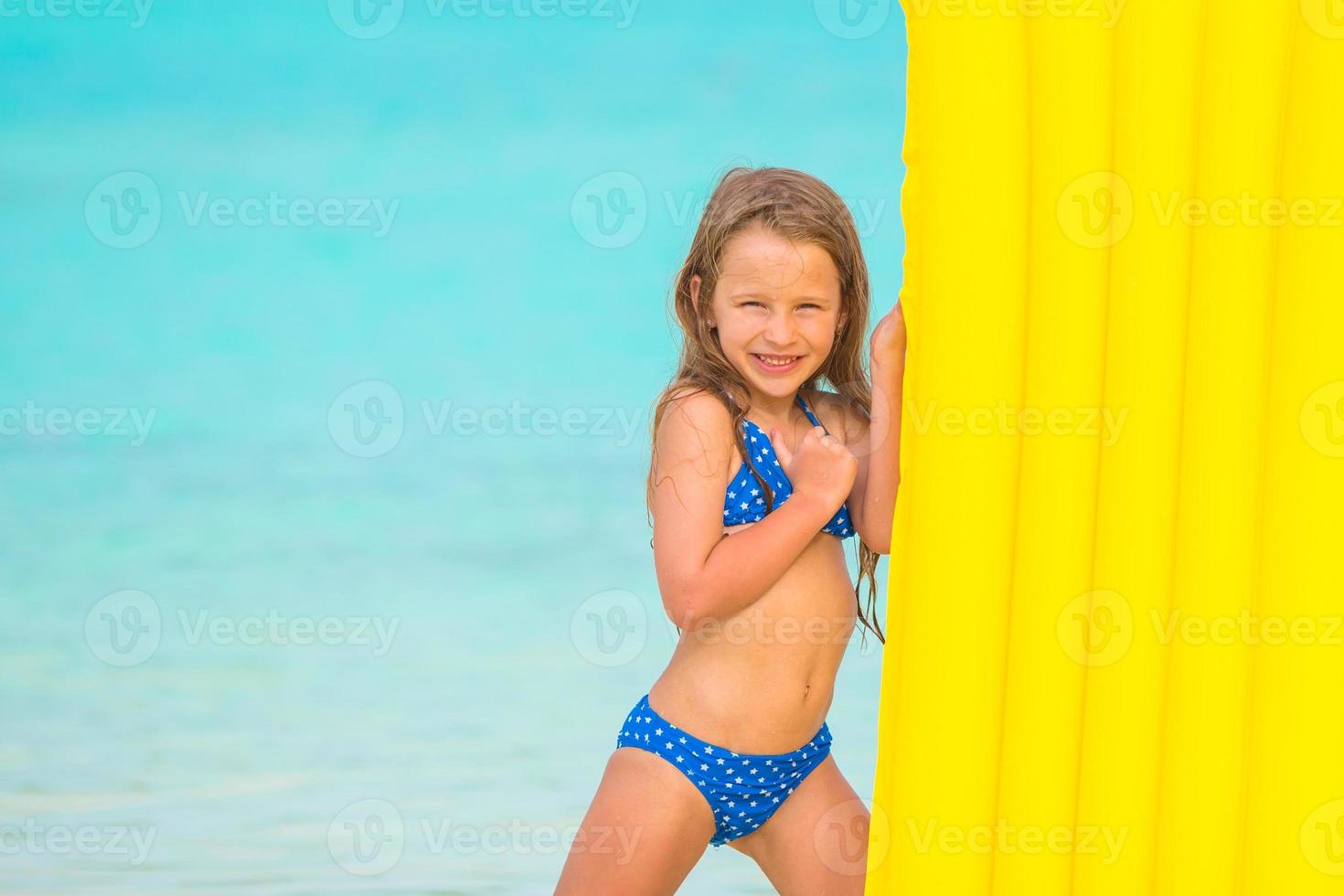 Little girl with air mattress on summer vacation at tropical beach photo