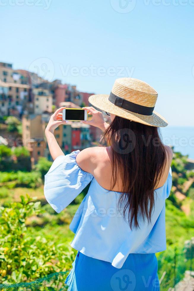 mujer joven toma una foto de la hermosa vista en el antiguo pueblo de cinque terre, liguria, italia. vacaciones italianas europeas.