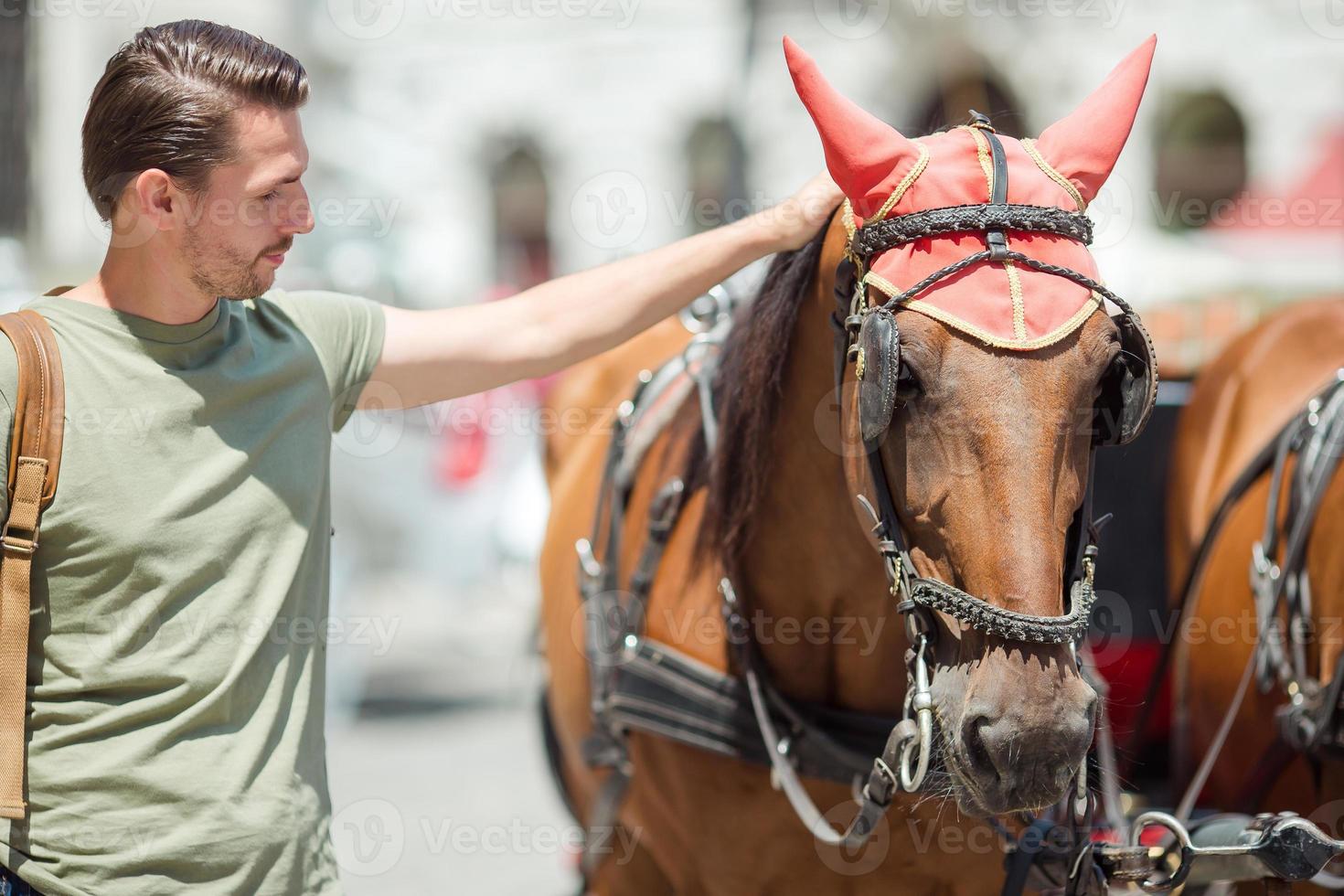 Tourist man enjoying a stroll through Vienna and looking at the beautiful horses in the carriage photo