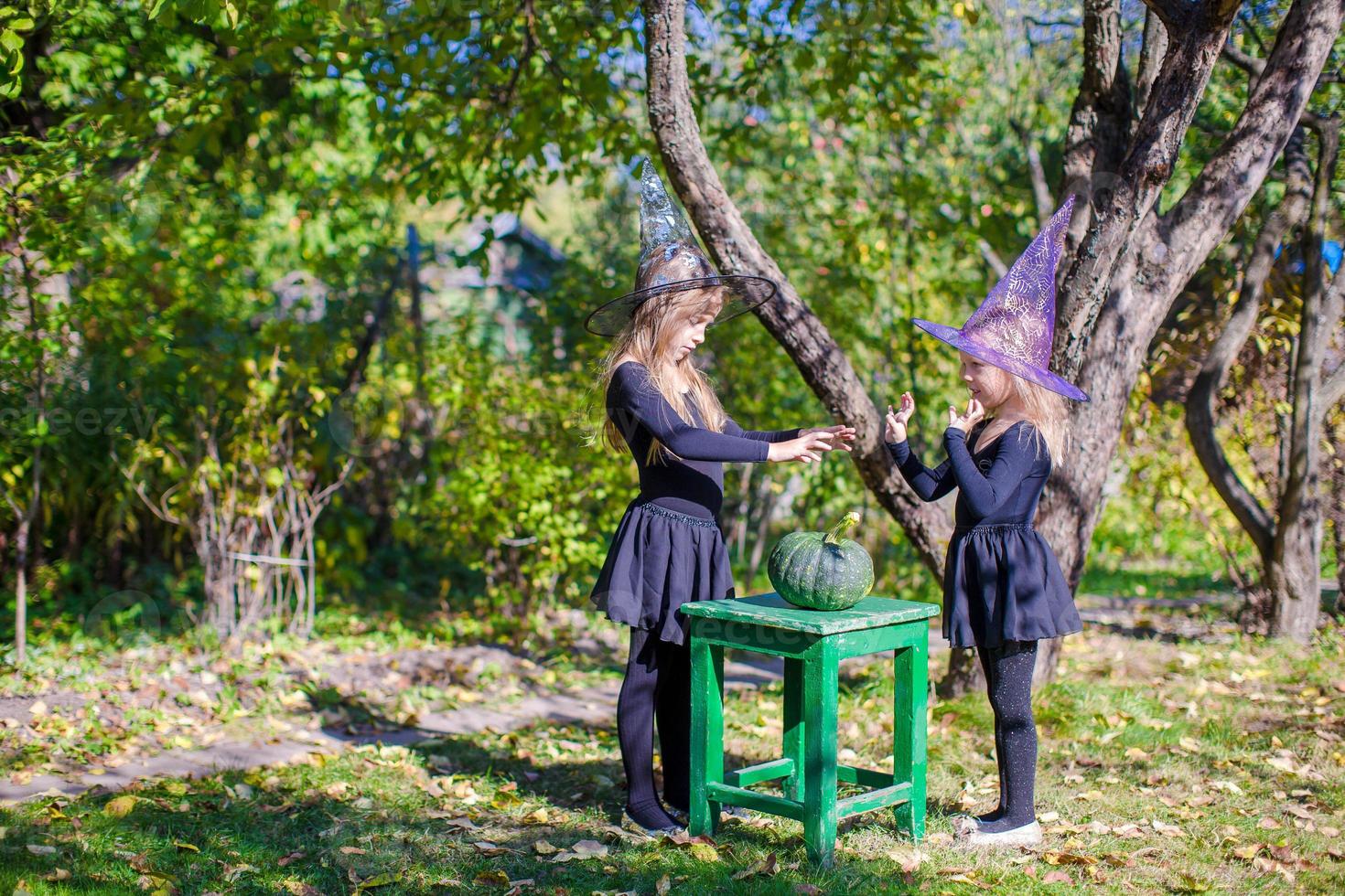 Adorable little girls in witch costume on Halloween outdoors photo