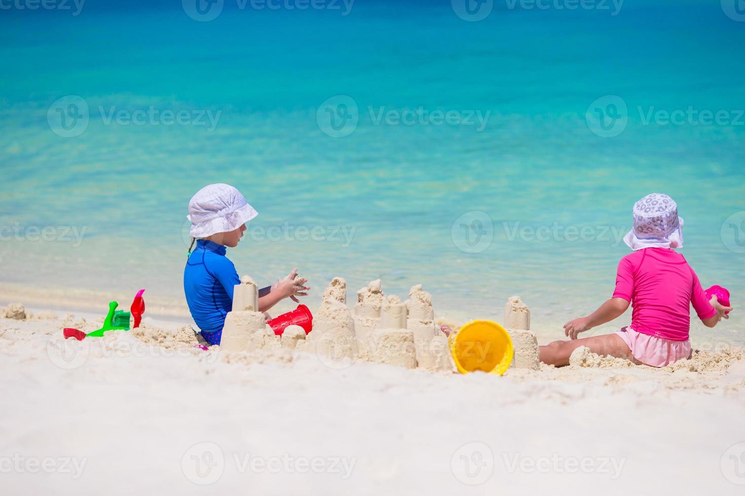 adorables niñas jugando con juguetes de playa durante las vacaciones tropicales foto