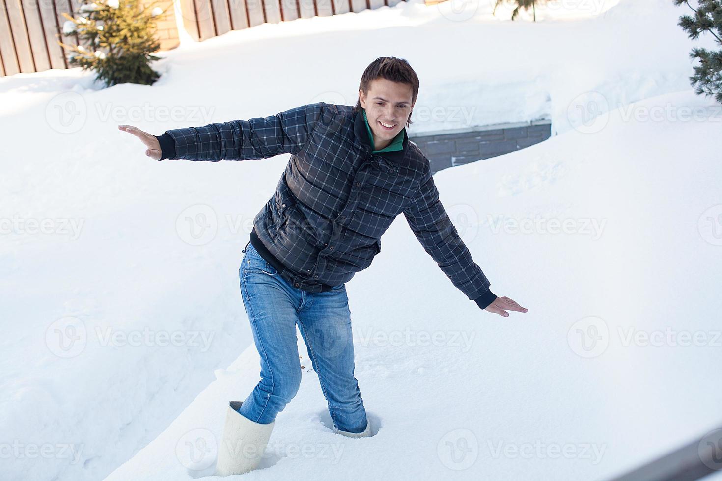 Young man in winter boots fell into a deep white snow photo
