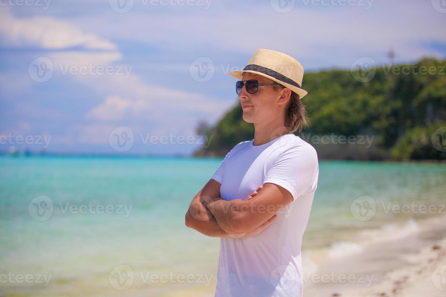 Young man standing on white beach photo