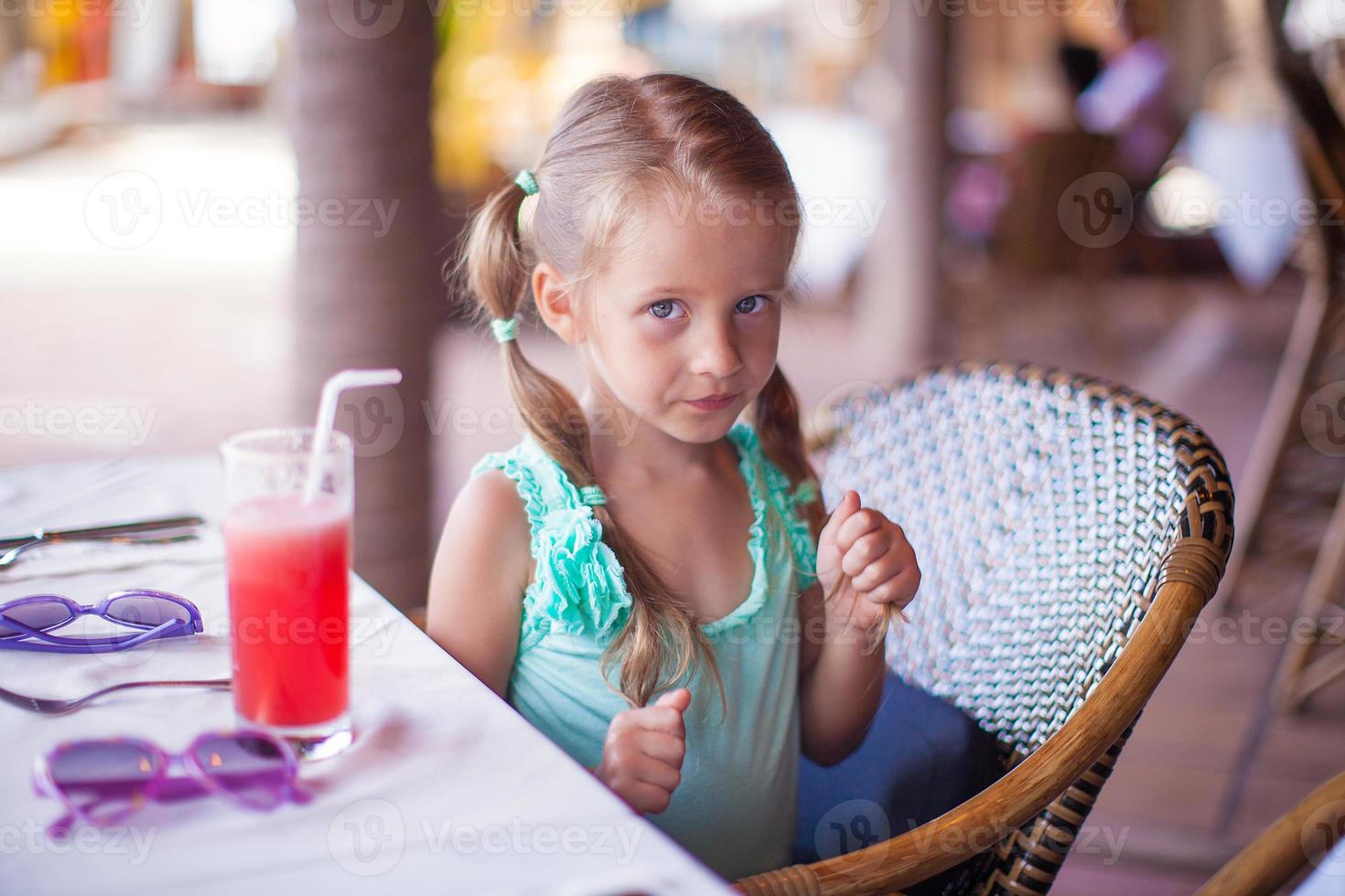Little girl sitting in chair at restaurant waiting for her food photo