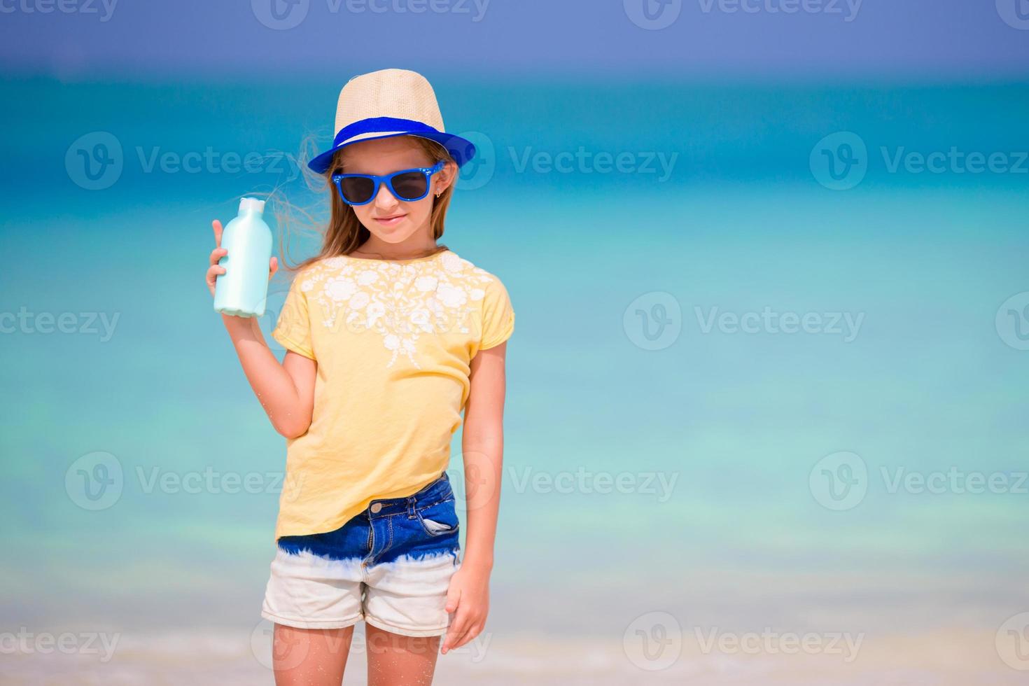 Little adorable girl with suntan lotion bottle on the beach 17753617