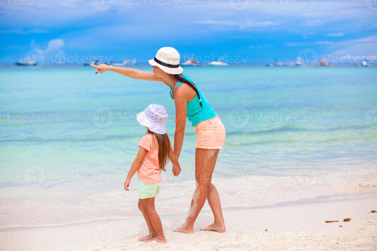 vista trasera de la madre señalando a la pequeña hija del mar foto