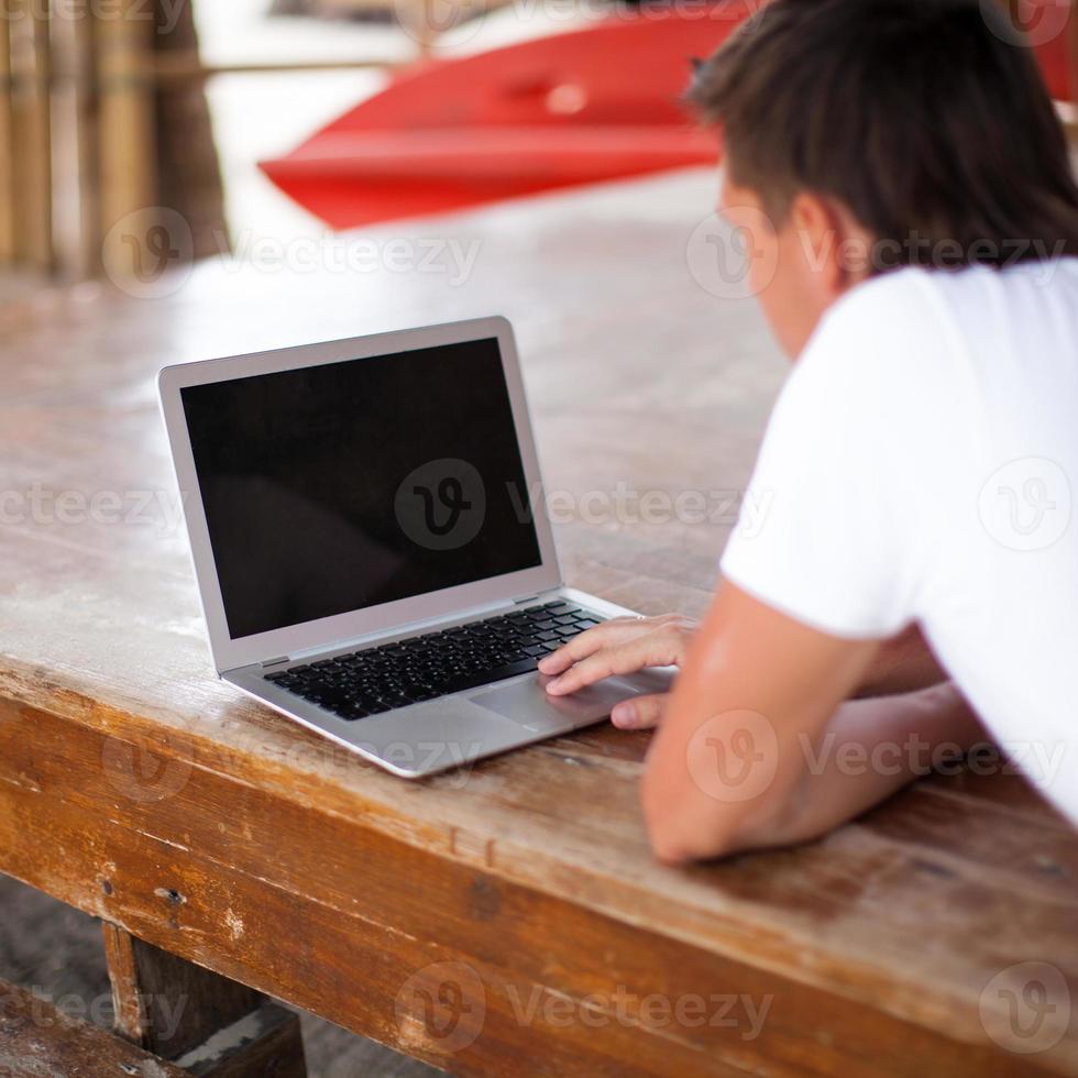 Back view of young man with laptop outdoor on vacation photo