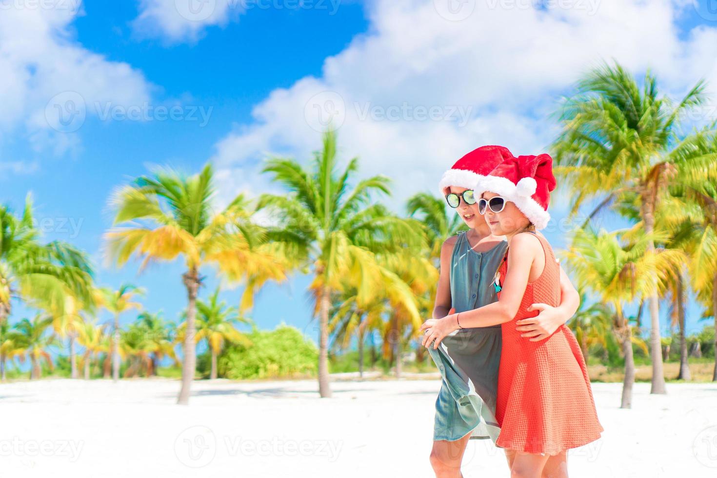 adorables niños pequeños se divierten con sombrero de santa celebrando la navidad en la playa foto