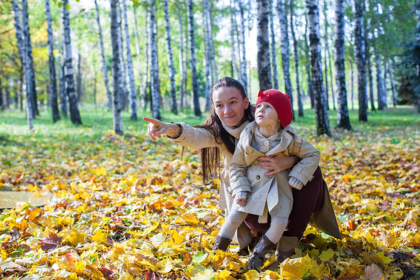 Fashion young mother and her adorable little daughter enjoying a sunny day in autumn park photo