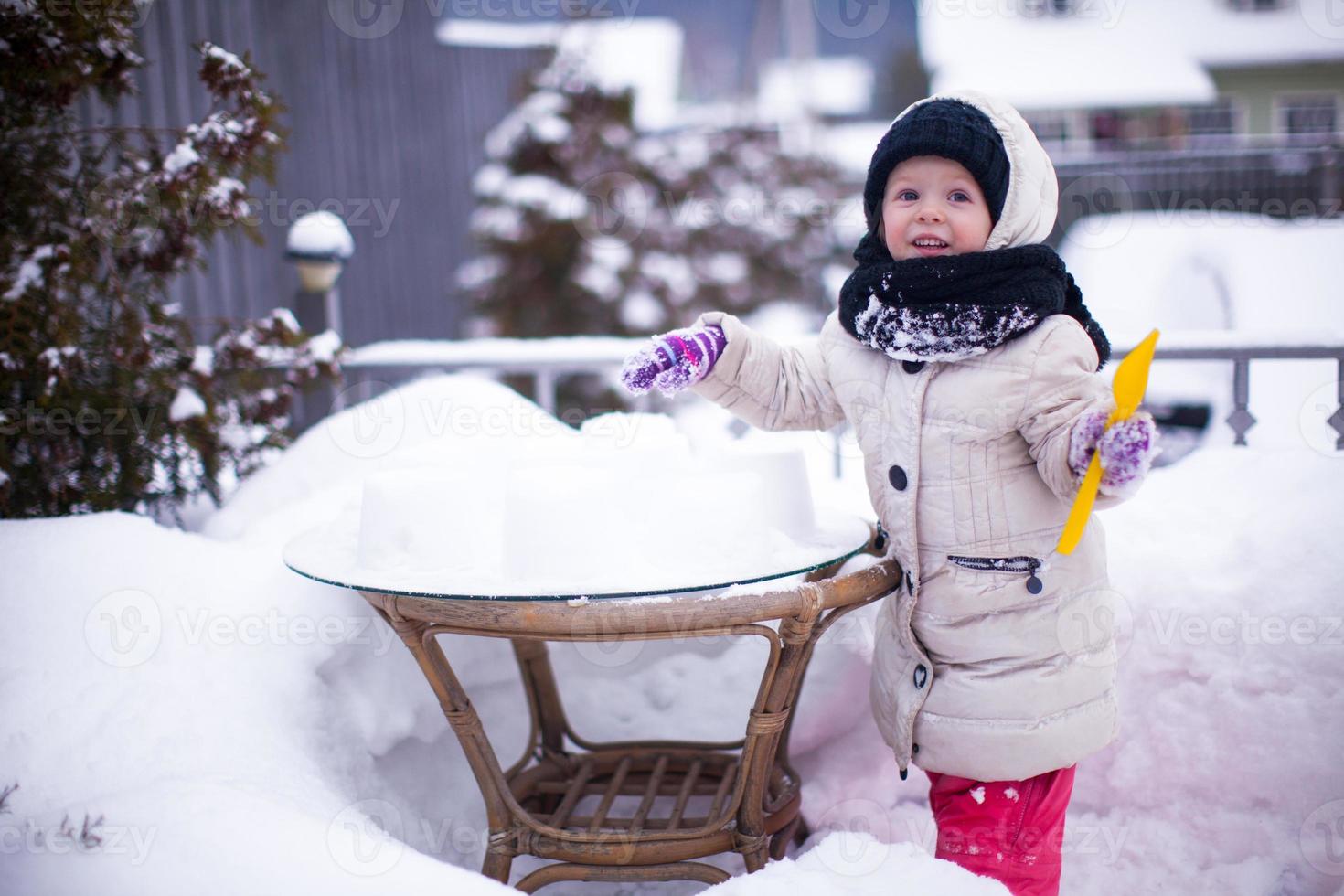 Little funny girl having fun and playing in the yard at winter sunny day photo