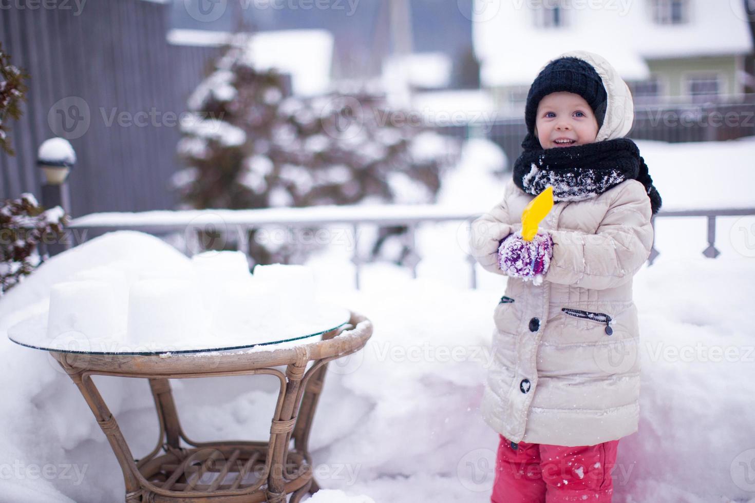 Little funny adorable girl having fun and playing in the yard at winter sunny day photo