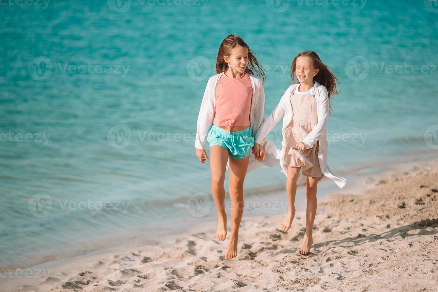 Little happy funny girls have a lot of fun at tropical beach playing together. photo